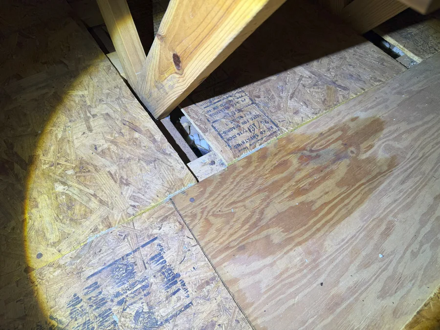 Water stains on attic roof decking lit by a flashlight